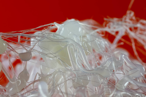 Drops and strands of hot glue have already cooled down and are visible against a red backgroun - Foto, Imagen