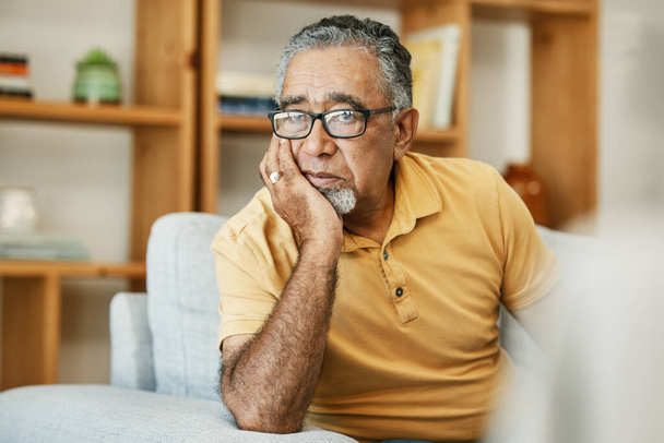 Gesicht, psychische Gesundheit und Denken mit einem traurigen alten Mann auf einem Sofa im Wohnzimmer seines Altersheims. Depressionen, Alzheimer oder Demenz und ein einsamer Senior mit Gedächtnisnostalgie. - Foto, Bild