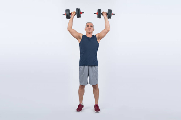 全身の長さショットアクティブでスポーティなシニアマンは,隔離された背景での体重トレーニングのトレーニング中にダンベルを持ち上げます. 年金受給者のための健康的なアクティブな体格とボディケアライフスタイル. クロート - 写真・画像