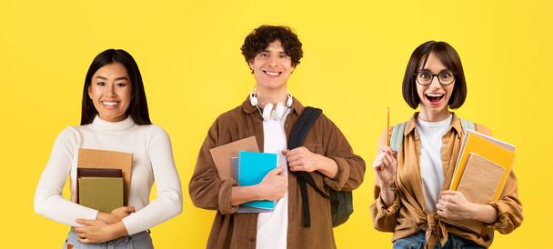 Studiuj reklamę. Happy podekscytowani wielonarodowi studenci pozowanie na tle żółtego studia, nurkowie młodzi mężczyźni i kobiety trzymając skoroszyty i plecaki, patrząc i uśmiechając się do kamery, Kolaż, Panorama - Zdjęcie, obraz