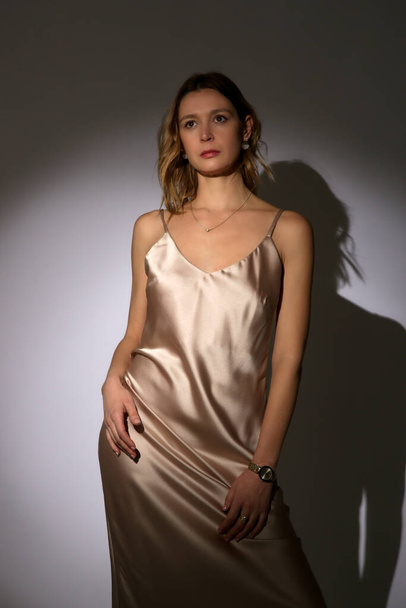 Серія студійних фотографій молодої жіночої моделі в елегантному шовковому камуфляжному сукні під прожектором. Класична і проста літня мода.  - Фото, зображення
