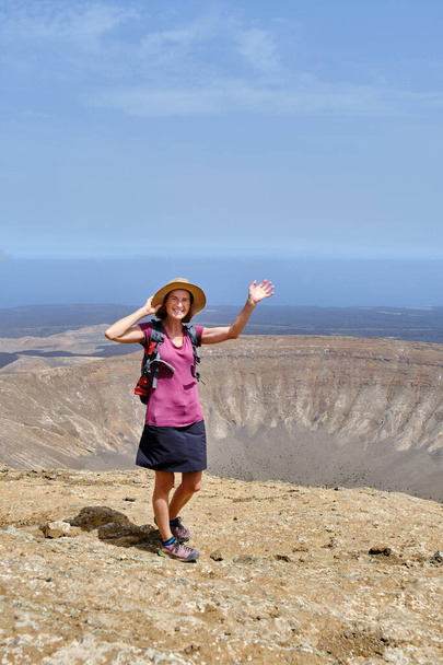 ハッピーな女性が火山クレーターの頂上に登ります. アドベンチャー・バケーション・コンセプト - 写真・画像