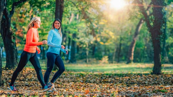 Freunde joggen im Freien, öffentlicher Park im Herbst.   - Foto, Bild