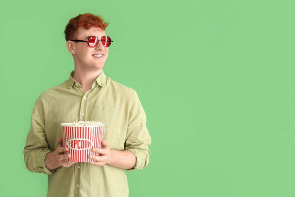 Jonge roodharige man met popcorn op groene achtergrond - Foto, afbeelding