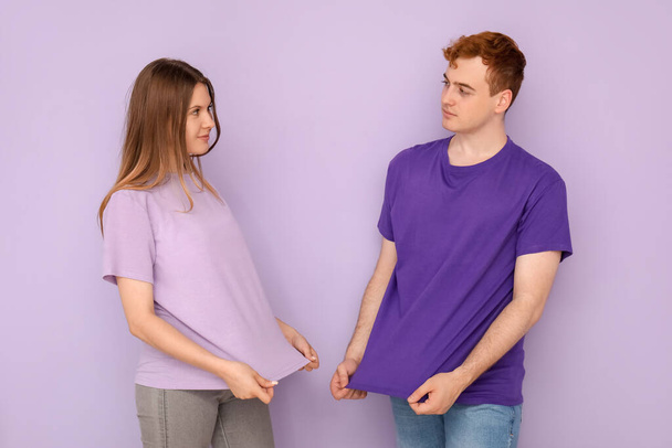 Young couple in t-shirts on lilac background - Photo, Image