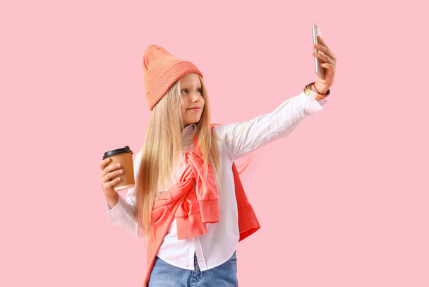 Niña con taza tomando selfie sobre fondo rosa - Foto, imagen