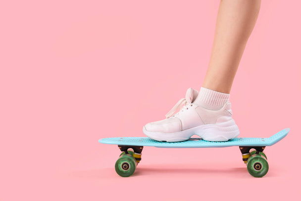 ピンクの背景にスケートボードを持つ若い女性, クローズアップ - 写真・画像