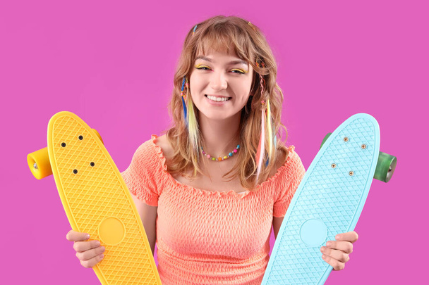 Mladá žena s skateboardy na fialovém pozadí - Fotografie, Obrázek