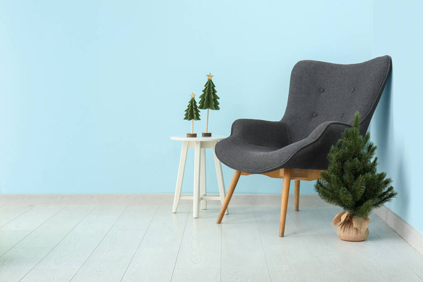 Interieur eines festlichen Wohnzimmers mit grauem Sessel und kleinem Weihnachtsbaum - Foto, Bild