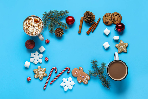 Cornice fatta di gustosi biscotti, cacao con marshmallow, bastoncini di zucchero, rami di abete, cannella, palle di Natale e fiocchi di neve su sfondo blu - Foto, immagini