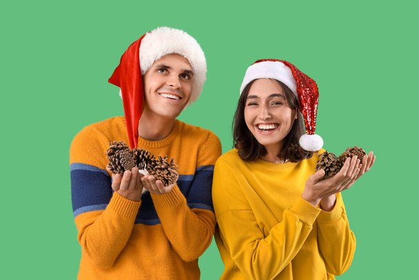 Joyeux jeune couple de chapeaux de Père Noël avec bosses de forêt sur fond vert - Photo, image