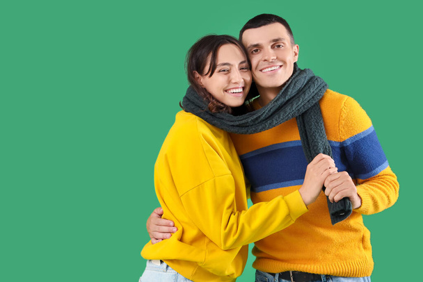 Happy young couple in warm clothes on green background - Foto, Bild