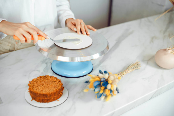 Confectionery, baking and cooking concept - woman making a cake in the kitchen at home. The process of creating a bento cake - Valokuva, kuva