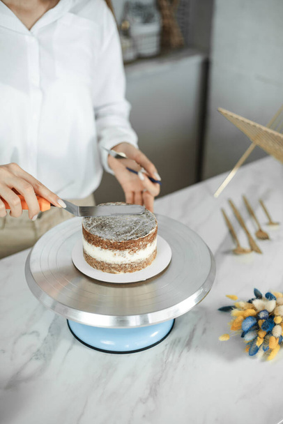Suikerwerk, bakken en koken concept - vrouw het maken van een taart in de keuken thuis. Het proces van het creëren van een bento cake - Foto, afbeelding