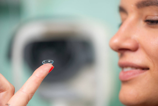 Geschoolde oogarts plaatst zachtjes zachte contactlens, zodat de patiënt comfort en helder zicht in een professionele klinische omgeving - Foto, afbeelding
