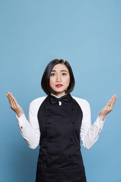 Restoran genç Asyalı kadın çalışanı kolları açık dua ediyor ve yukarı bakıyor. Cafe çekici garson profesyonel üniforma giyiyor meditasyon yapıyor, stüdyoda dinlenme çalışması yapıyor. - Fotoğraf, Görsel