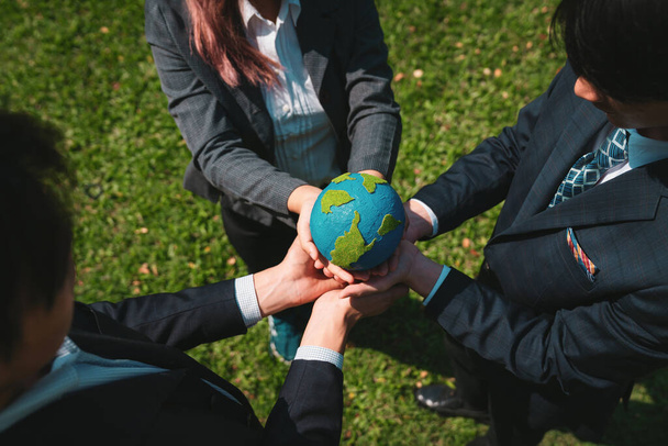 Group of business people hold planet Earth globe together as Earth day concept. Mission to save Earth by business commitment to environment friendly methods and sustainable practices. Gyre - Photo, Image
