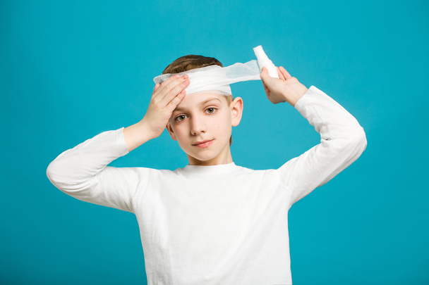 Boy taping up bandage on his head - Foto, afbeelding