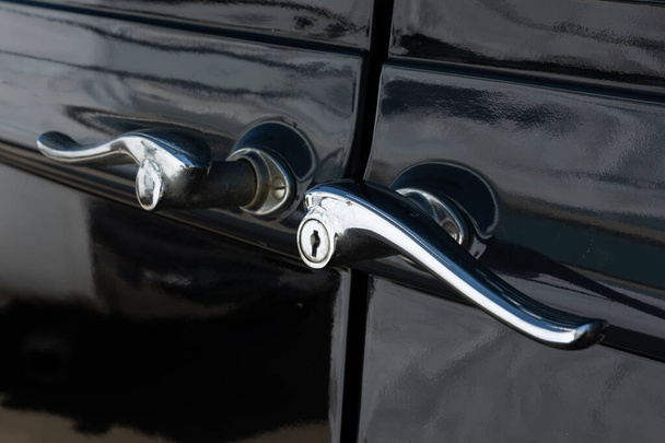 A close up of ornate suicide door handles on vintage black car. - Photo, Image