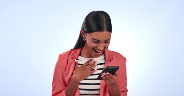 Indian woman in business, surprise for bonus on smartphone and prize for social media giveaway on blue background. Corporate reward, benefits and wow reaction for winning online competition in studio. - Footage, Video