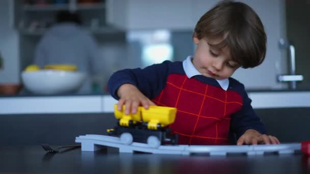 Niño pequeño juega con el juguete en casa. Niño imaginativo jugando con vagón amarillo en el ferrocarril - Imágenes, Vídeo