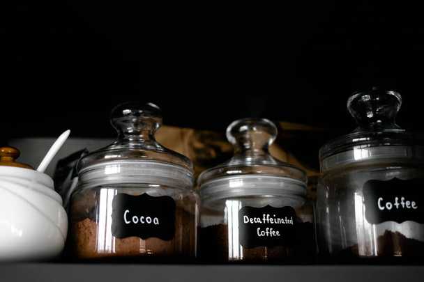 Plusieurs types de café moulu dans des récipients en verre sont sur l'étagère. Petit déjeuner café concept. Processus de fabrication du café à la maison. - Photo, image