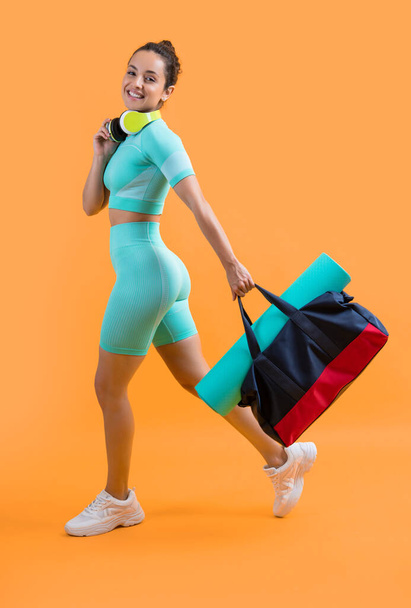 cheerful fitness woman in sportswear walk with sport bag in studio. fitness woman in workout sportswear isolated on yellow background. fitness and sportswear. - Foto, immagini