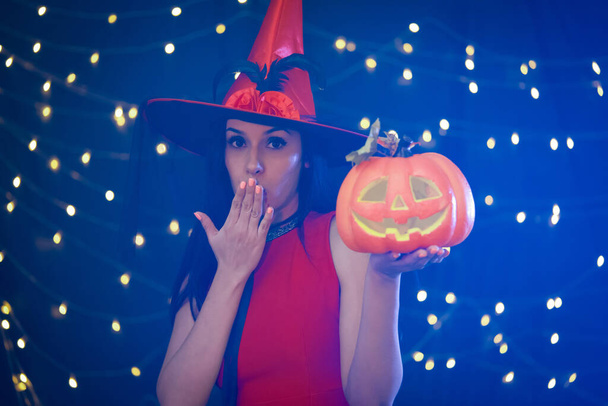 Spooky Fun avec une sorcière et une citrouille. L'essence enchanteresse d'Halloween avec l'image d'une femme portant un chapeau de sorcière, tenant gracieusement une citrouille vibrante et magnifiquement sculptée. - Photo, image
