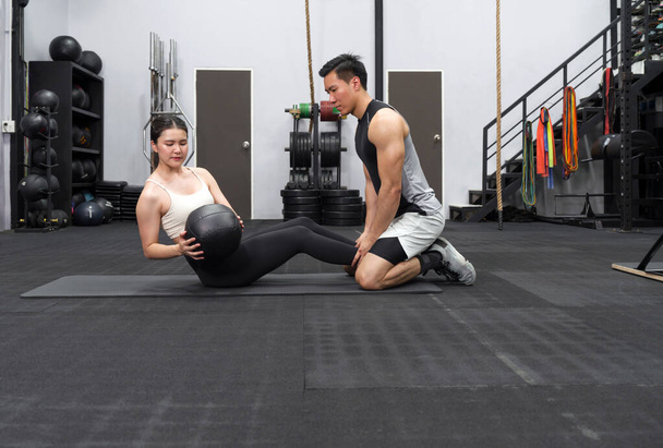 Ein fittes Paar, das in einem gut ausgestatteten Fitnessstudio eine Trainingsroutine ausübt, deren Engagement und Teamwork klar sind. - Foto, Bild