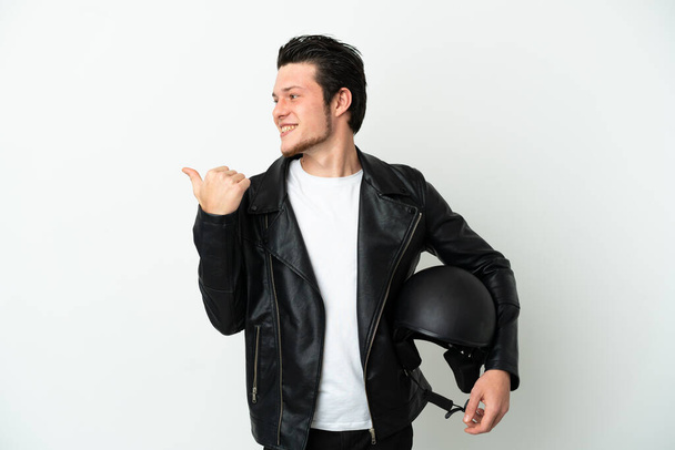 Ruský muž s motocyklovou přilbou izolované na bílém pozadí ukazuje do strany prezentovat produkt - Fotografie, Obrázek
