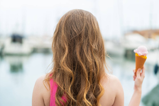 Kornet dondurmalı genç kızıl saçlı kadın arka tarafta. - Fotoğraf, Görsel