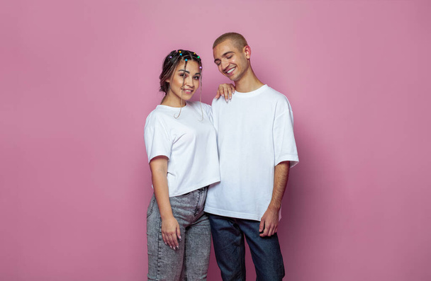 Atraktivní mladá žena a muž na sobě bílé prázdné tričko na jasně růžové studio zeď banner pozadí - Fotografie, Obrázek