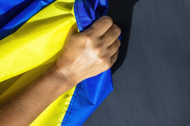 Ruku na ukrajinskou vlajku. Ukrajinská vlajka je prapor dvou stejně velkých vodorovných pruhů modré a žluté. - Fotografie, Obrázek
