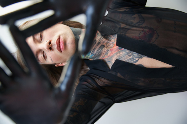 stylish handsome young man with tattoos posing with hands in front of his face, fashion concept - Photo, Image