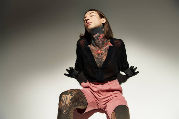good looking young man with tattoos and piercing posing on floor with closed eyes, fashion concept - Foto, Imagen