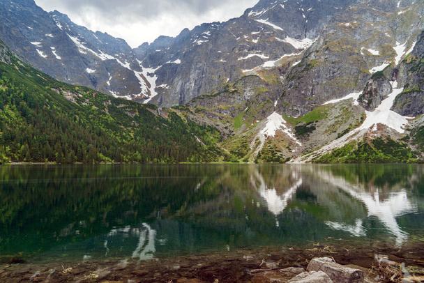 A serene mountain landscape with reflections in Morskie Oko lake, a renowned spot in Poland's Tatra National Park. Perfect for nature, travel, and adventure themes - Photo, Image