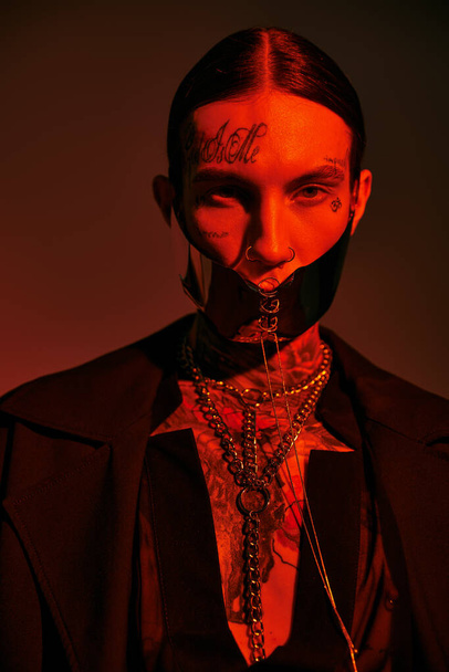 tiro vertical de hombre joven con estilo en la máscara atada futurista con tatuajes en la cara, concepto de moda - Foto, Imagen