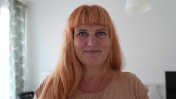 attraktive Frau mittleren Alters mit roten Haaren macht feuchtigkeitsspendende Augenmaske aus Gurkenscheiben, zu Hause. - Filmmaterial, Video