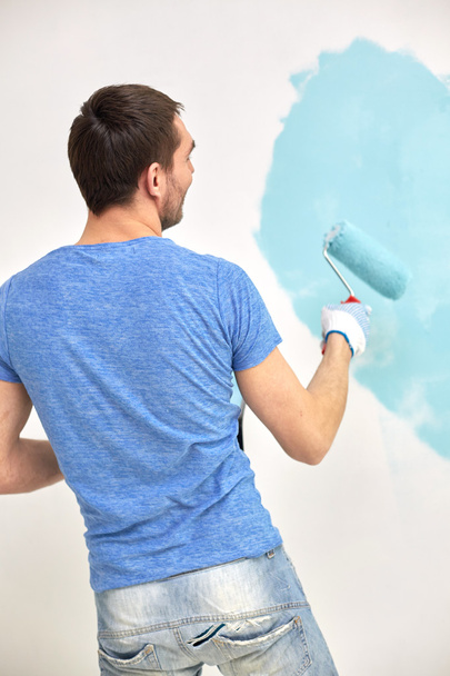 hombre con la pared de la pintura del rodillo en azul en casa
 - Foto, Imagen