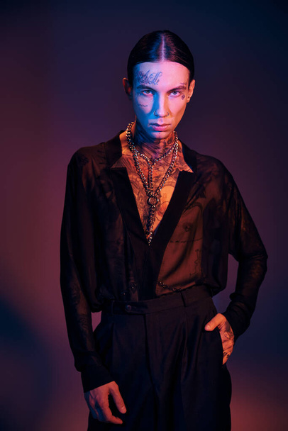 vertical shot of alluring young man in transparent shirt with tattoos looking at camera, fashion - Fotó, kép