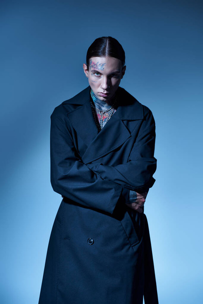 joven guapo con tatuajes y envoltura piercing en su abrigo negro mirando a la cámara, la moda - Foto, Imagen