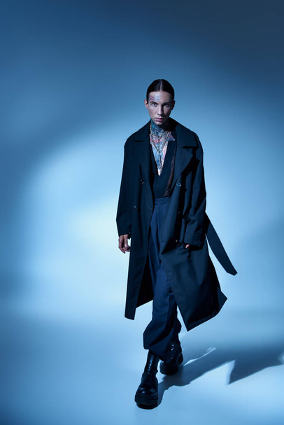 vertical shot of young stylish male model with tattoos in black voguish coat looking at camera - Photo, Image