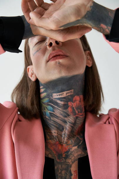 vertical shot of young handsome man with tattoos with hands near face and closed eyes, fashion - Фото, зображення