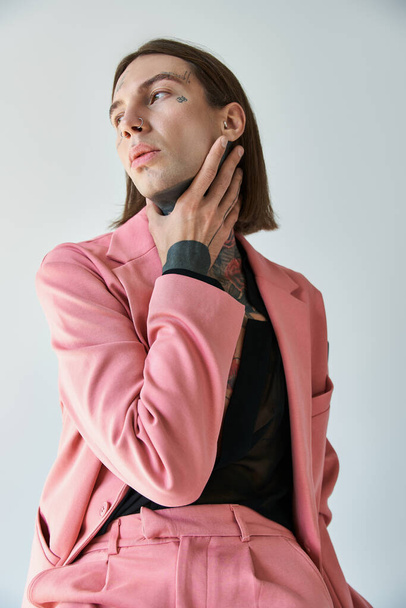függőleges lövés voguish fiatal férfi rózsaszín blézer és rövidnadrág kéz a nyakon néz félre - Fotó, kép