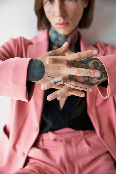 se centran en las manos con tatuajes de hombre joven y elegante borrosa en traje rosa y negro, concepto de moda - Foto, Imagen