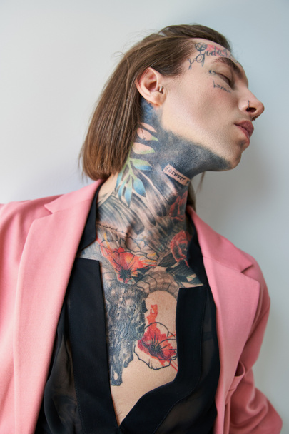 alluring young man in pink blazer and transparent black shirt posing and looking away, fashion - Photo, Image