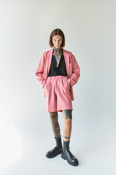 tiro vertical de hombre con estilo de buen aspecto en chaqueta rosa y pantalones cortos mirando a la cámara, la moda - Foto, imagen