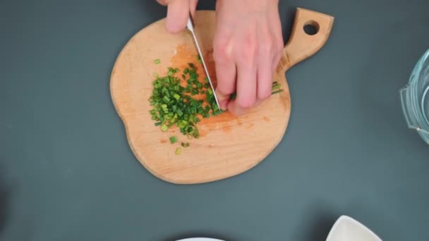 Kadınların elleri ahşap bir tahtanın üzerinde bıçakla çabucak soğan keser. Mutfak masasının üst manzarası. Mutfakta yemek pişirmek. - Video, Çekim