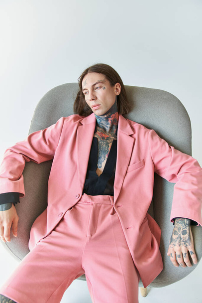 vertical shot of good looking sexy man in stylish pink blazer relaxing on chair, fashion concept - Фото, зображення