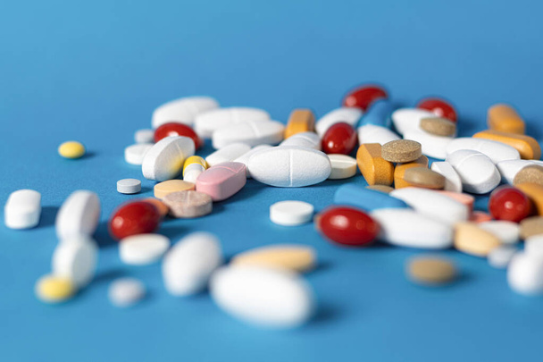 Pills on a blue, medical background. Pile of medicine pills. Background with colorful pills and capsules. Copy space - Photo, Image